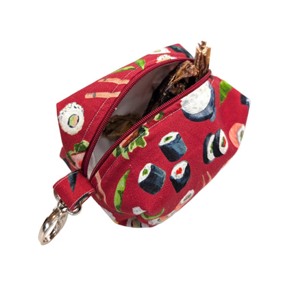 A small zippered pouch with a sushi print in red, shown open with a silver key ring attachment on a white background.